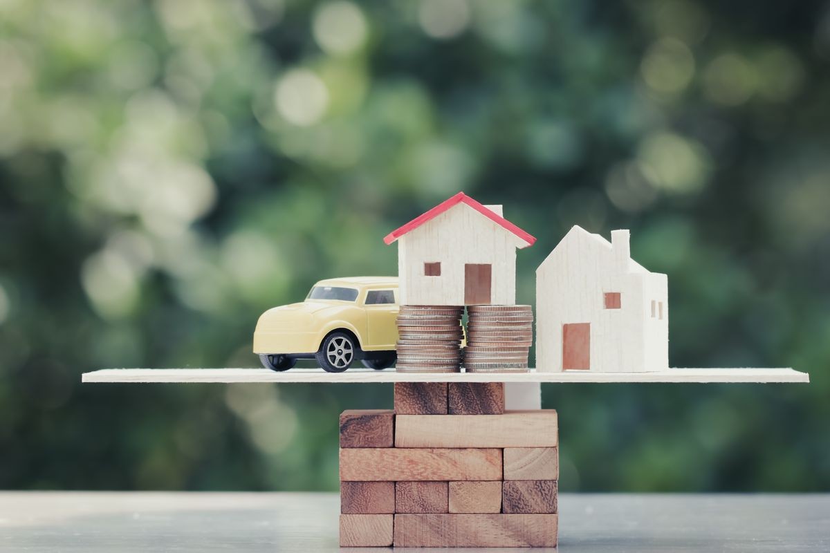 Business real estate investment concept : Wooden home, car with stack of money coins on wooden blocks scale in balance on green background. Savings plans housing, loan money. Investing is risky.